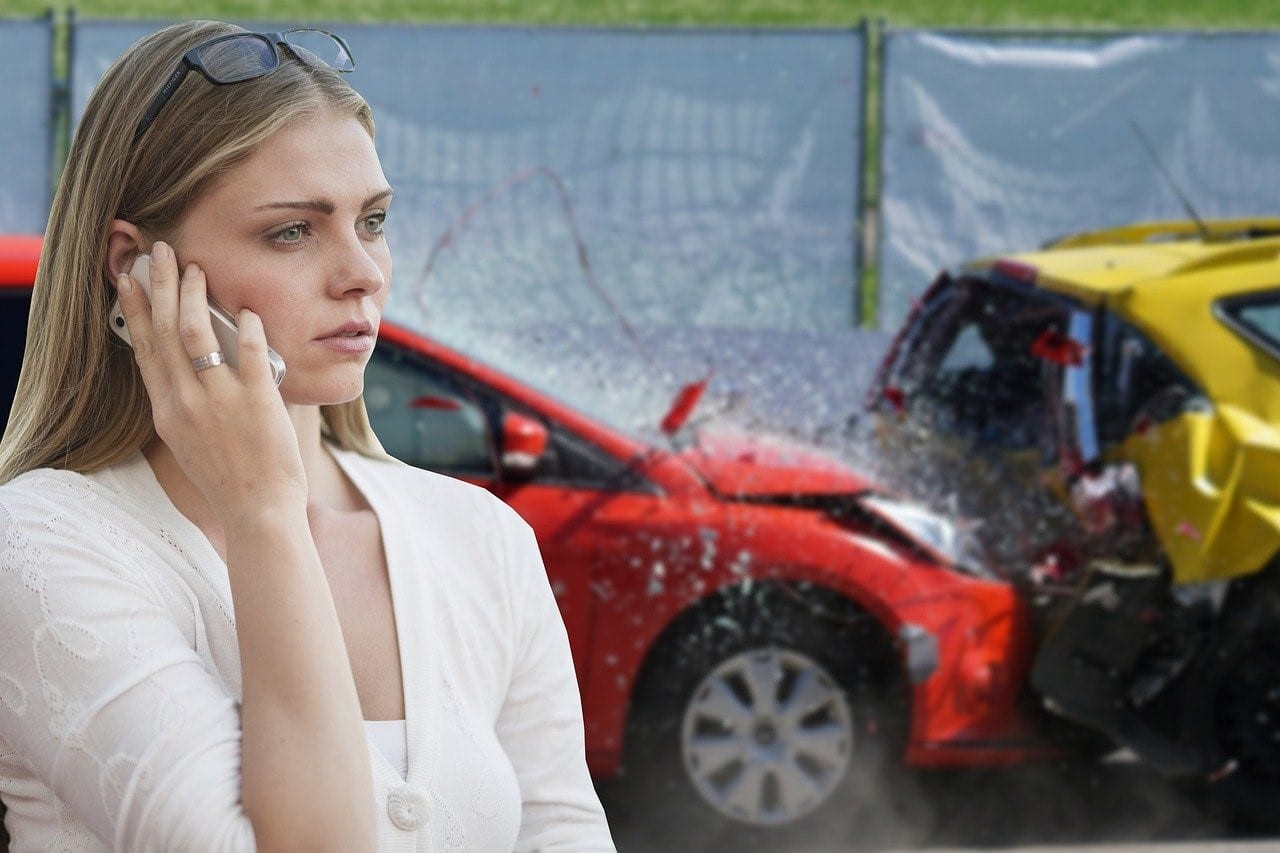 Woman involved in a car collision using her phone to call for assistance