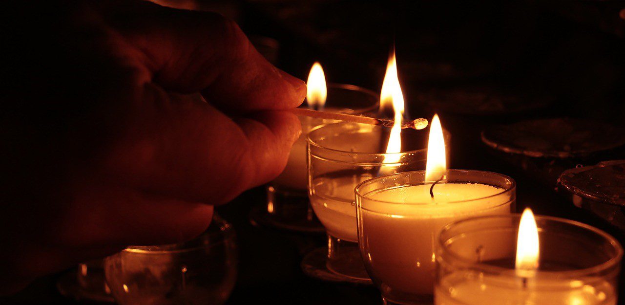 Person lighting a candle for traffic accident casualties