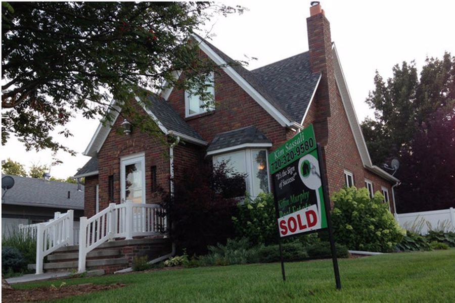 Brick house with a sign in front of it