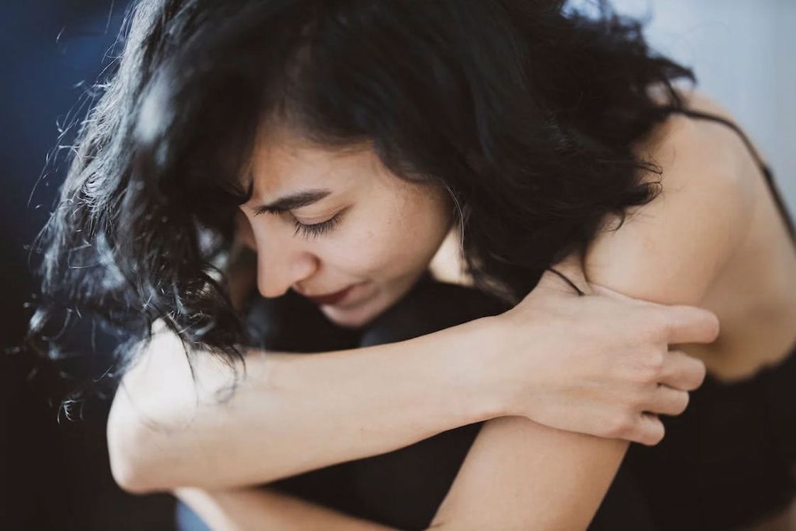 Woman looking pained while hugging herself