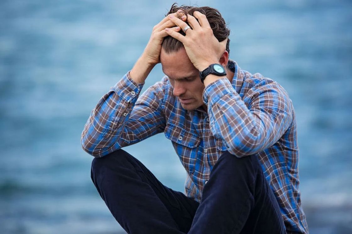 Man in plaid dress shirt touching his hair