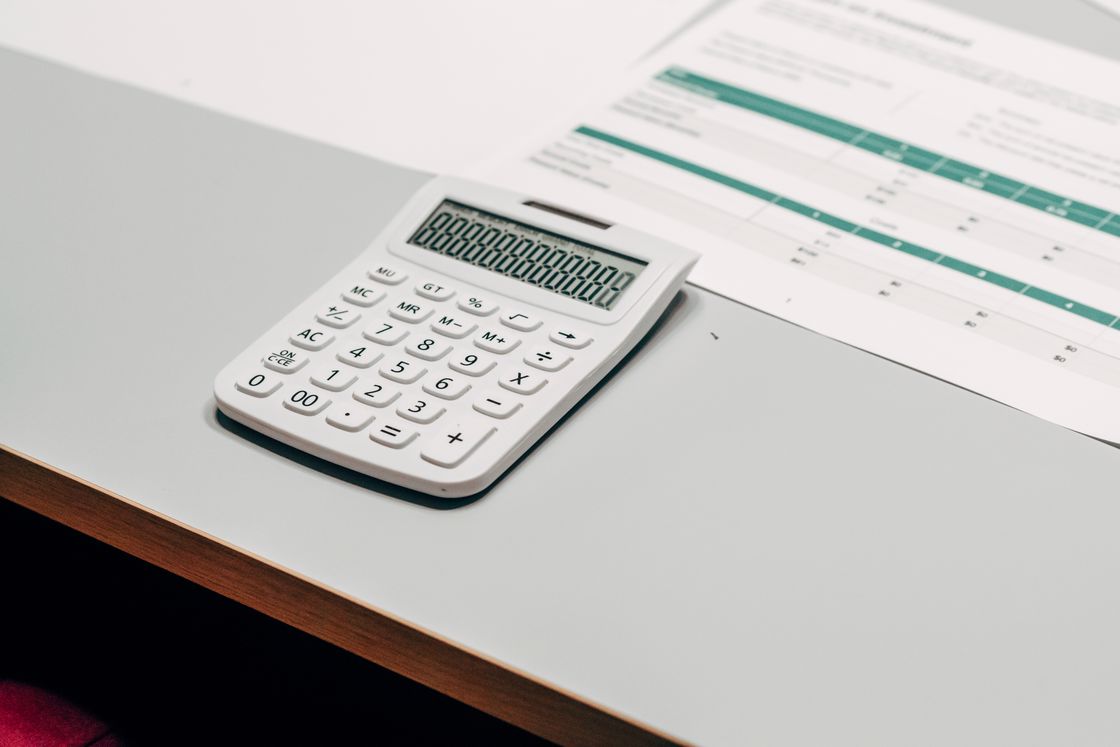 White calculator beside a data sheet on a table