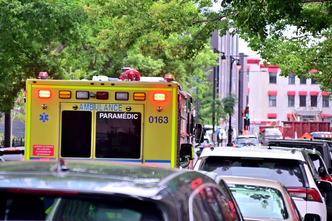 Yellow ambulance stuck in traffic with a crowded roadway