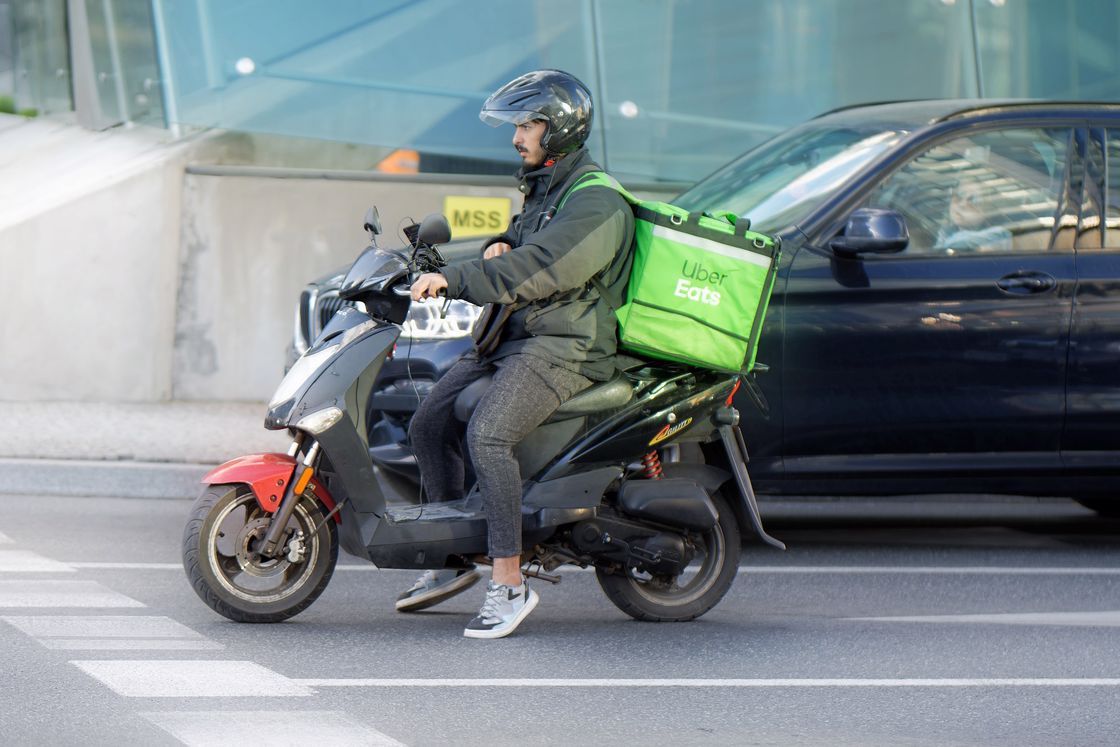 Man driving with a geen UberEats delivery box attached on his black motorcycle