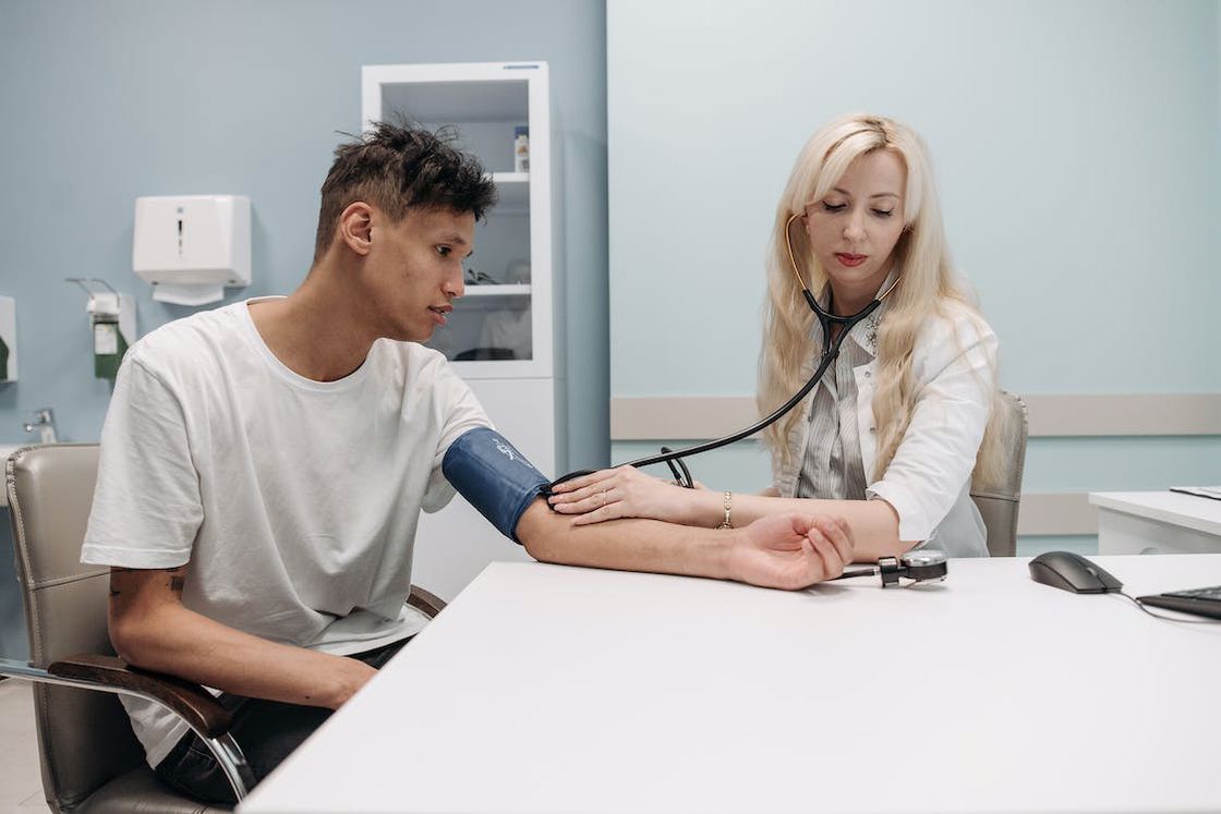 Woman doctor trying to check her male patient's blood pressure