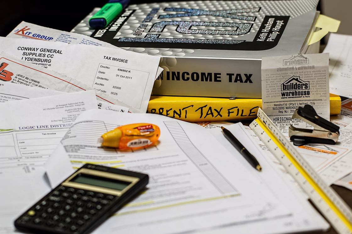 Calculator, binders and papers laid on the table in preparation for tax filling