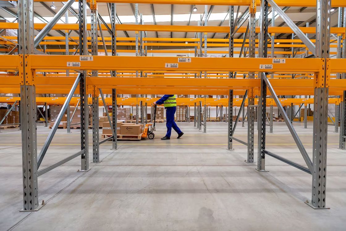 Employee pushing a trolley filled with packages inside a warehouse