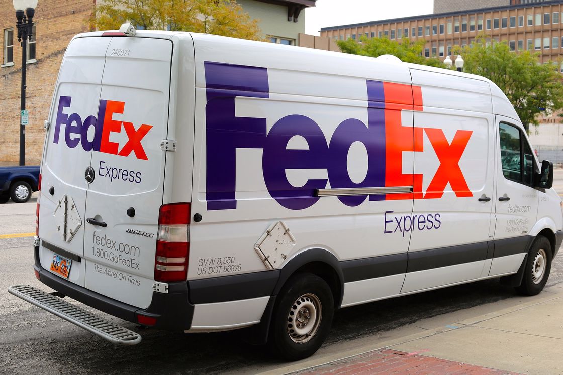 White FedEx truck parked right across a building