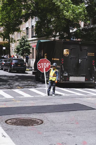 Traffic aide holding a stop sign with a UPS truck visible in the background