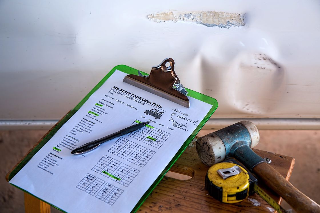 Checklist of insurance related car repairs with a hammer and measuring tape beside it