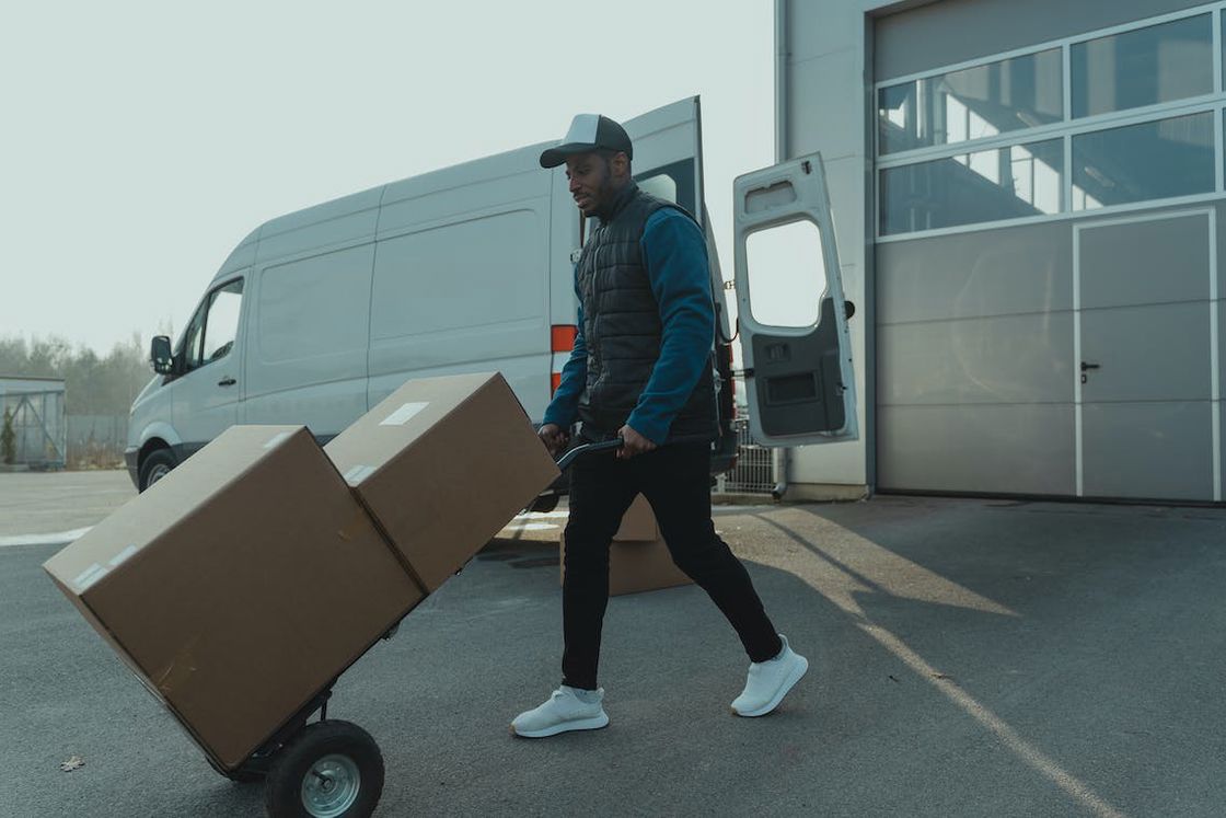 Man pushing the trolley filled with packages from his delivery van