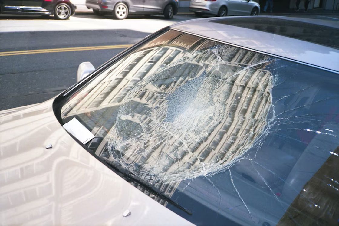 Badly damaged car windshield parked on the side of the street