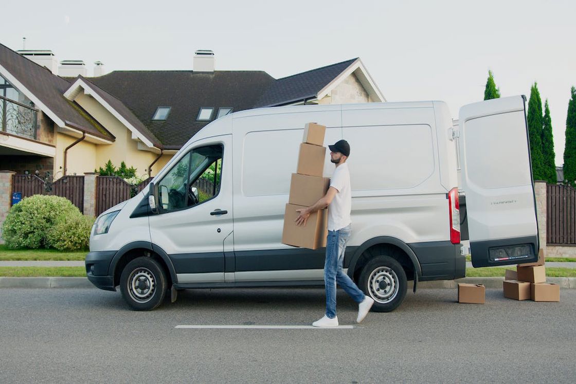 Delivery driver holding a stack of boxes from a delivery van