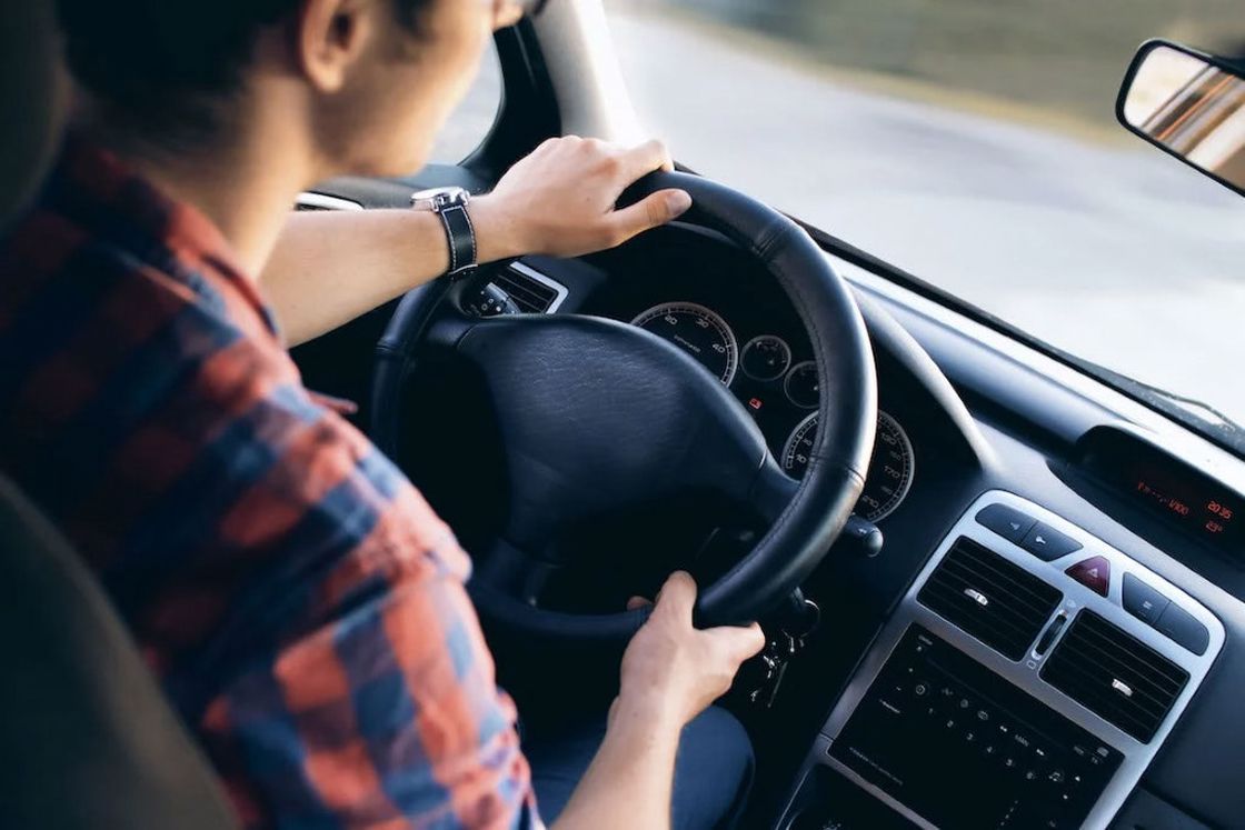 Woman in a plaid shirt holding the car's steering wheel while out on a drive