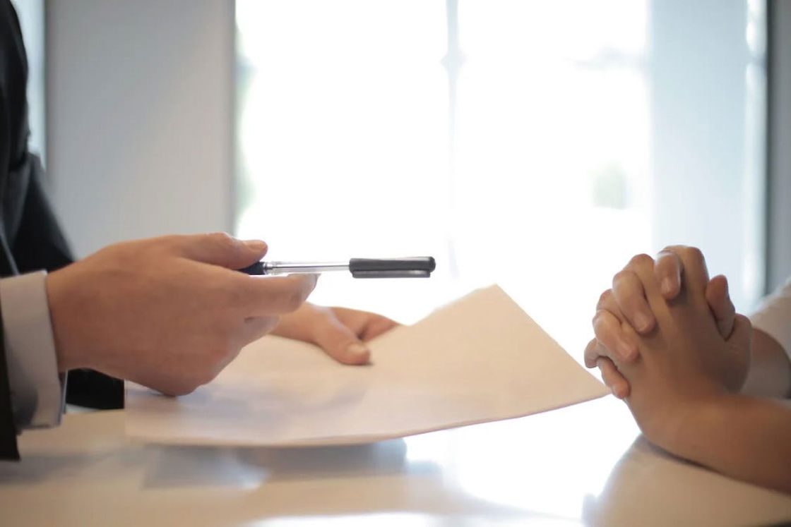 Person handing out a pen and documents to a client