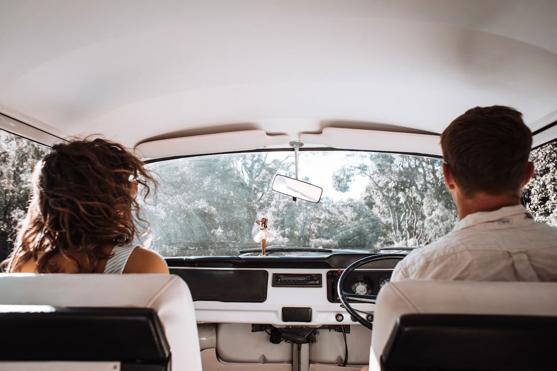 Couple driving their white car on a forest road