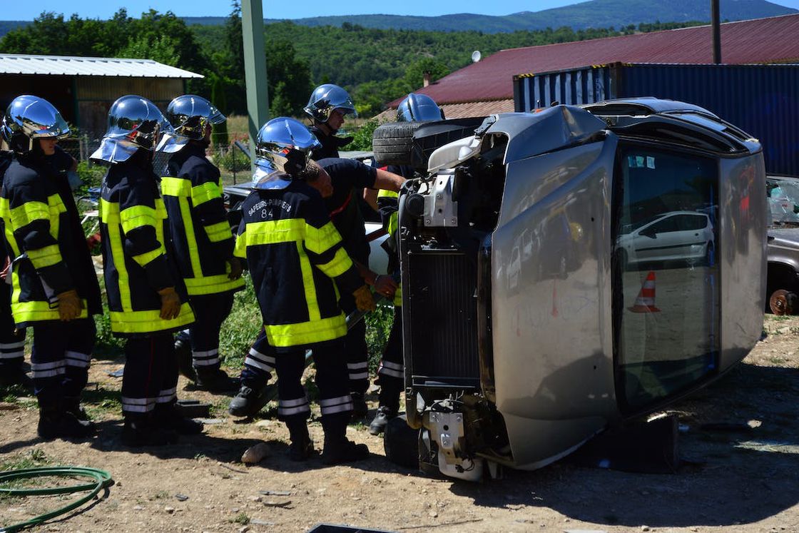 Firefighters trying to turn a car over after it was thrown sideways after an accident