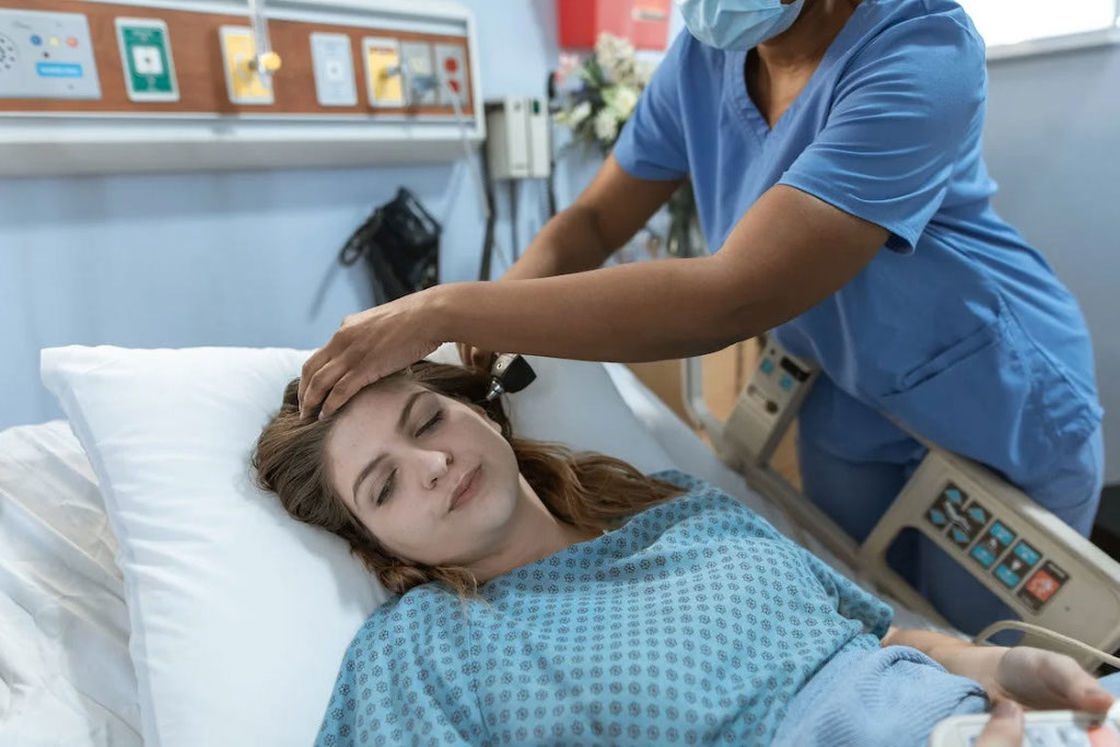 Doctor checking a patient's ear while she's lying down on a hospital bed