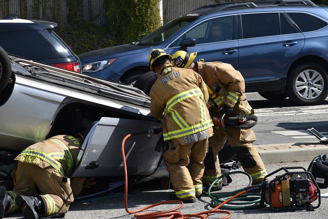 Firefighters working together to remove a victim from a car that toppled down after an accident