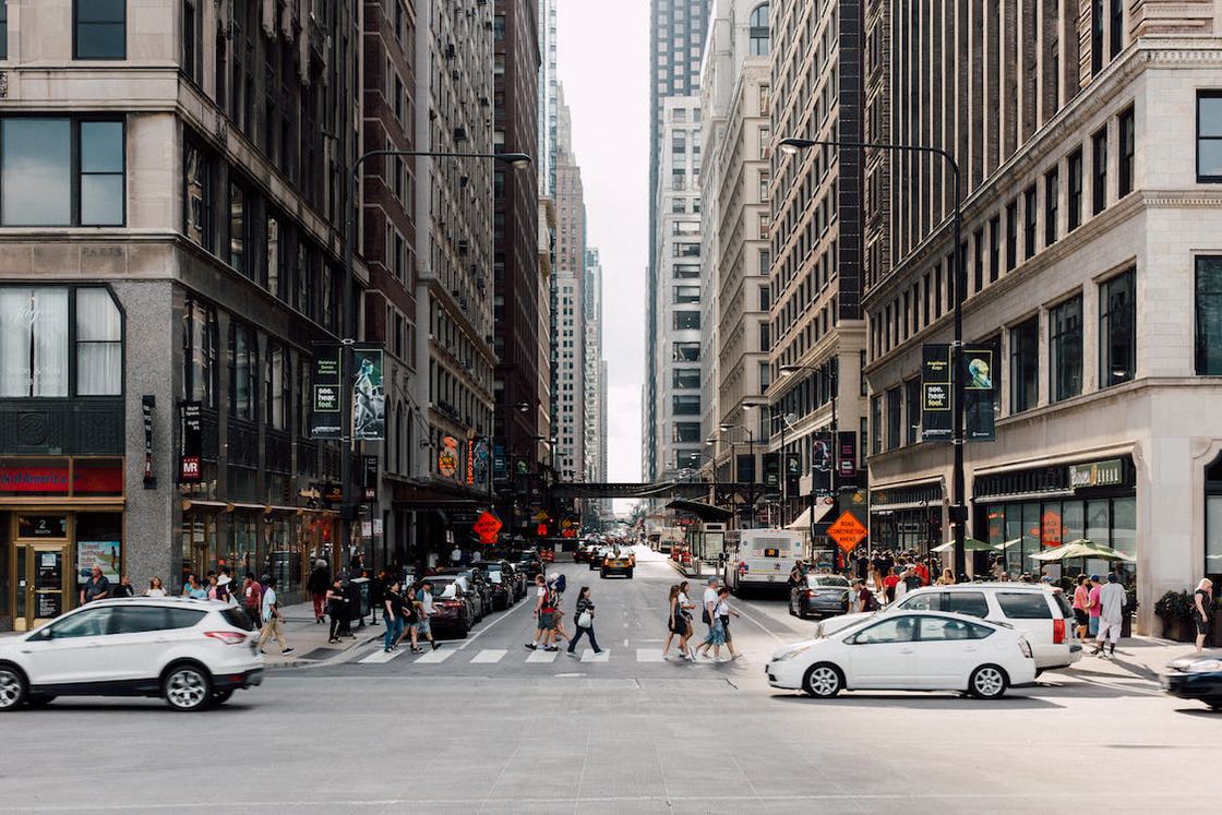 Cars passing near the road where people are walking in a pedestrian crosswalk