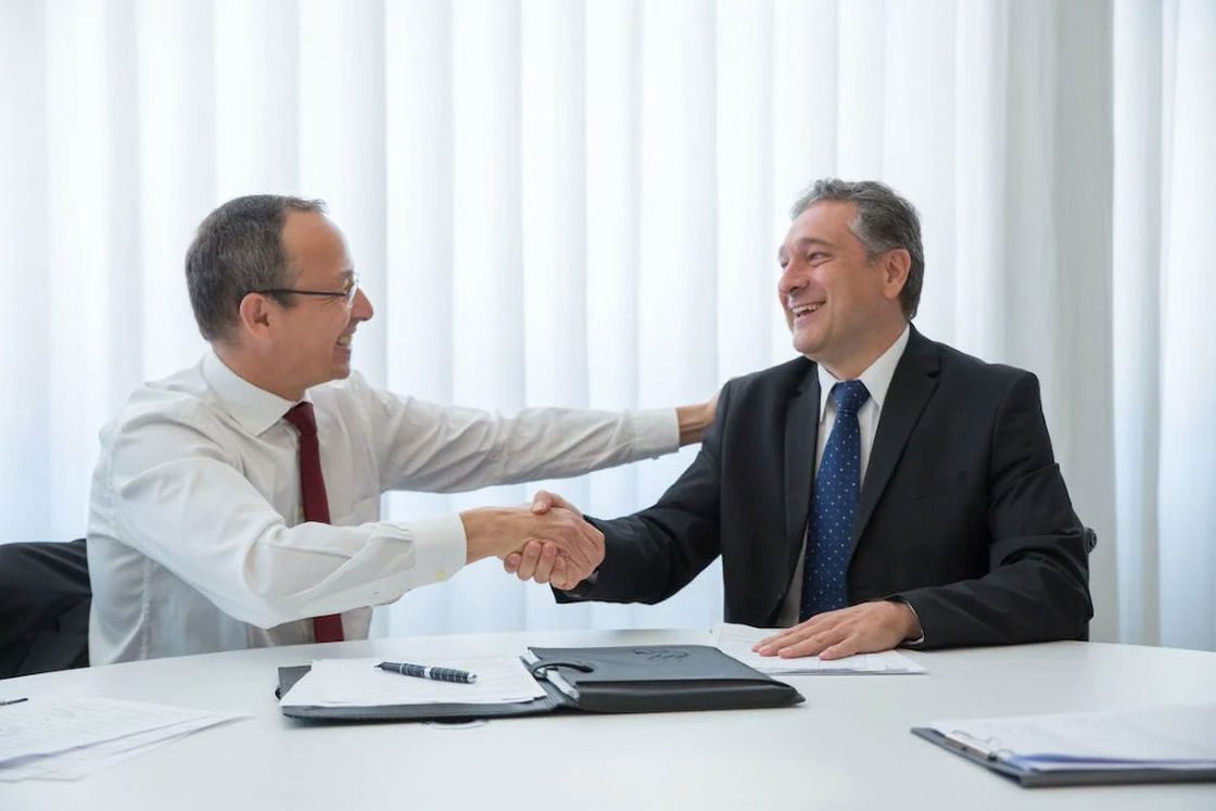 Two men shaking hands in agreement after a meeting