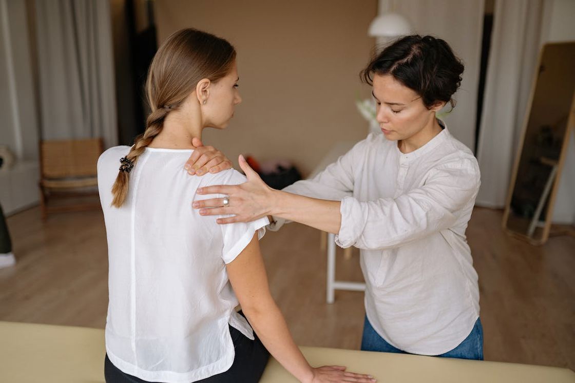 Therapist massaging a woman's shoulders on a therapy bed