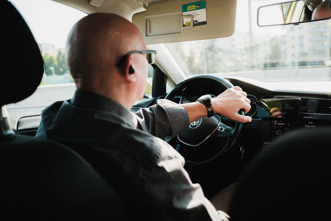 Man with his hand on the steering wheel while driving his car