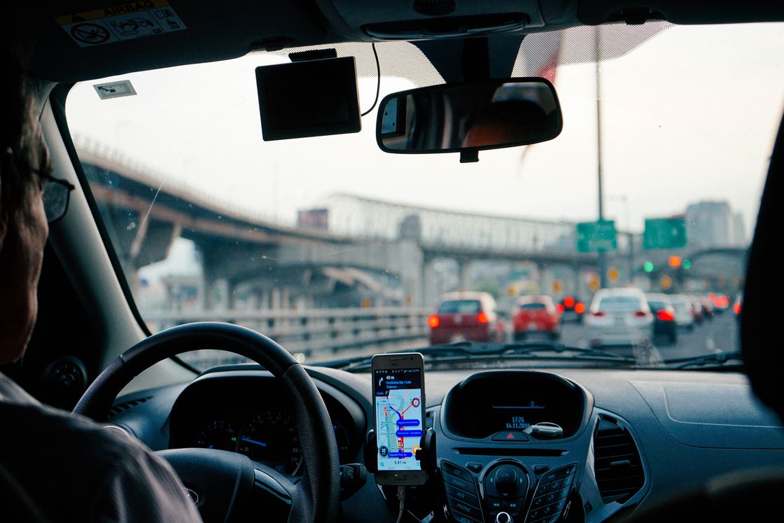 Person using Google Maps on his phone for directions as he drives in his car