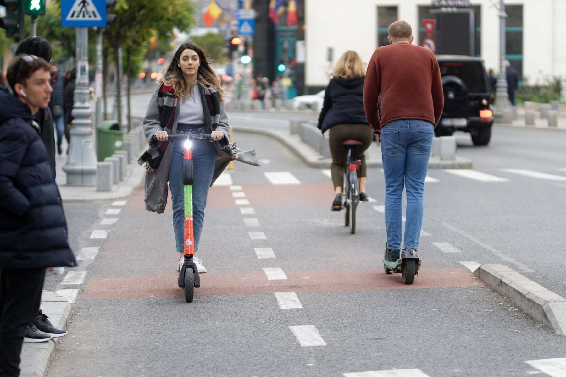 Woman riding an e scooter in a side street close to the sidewalk