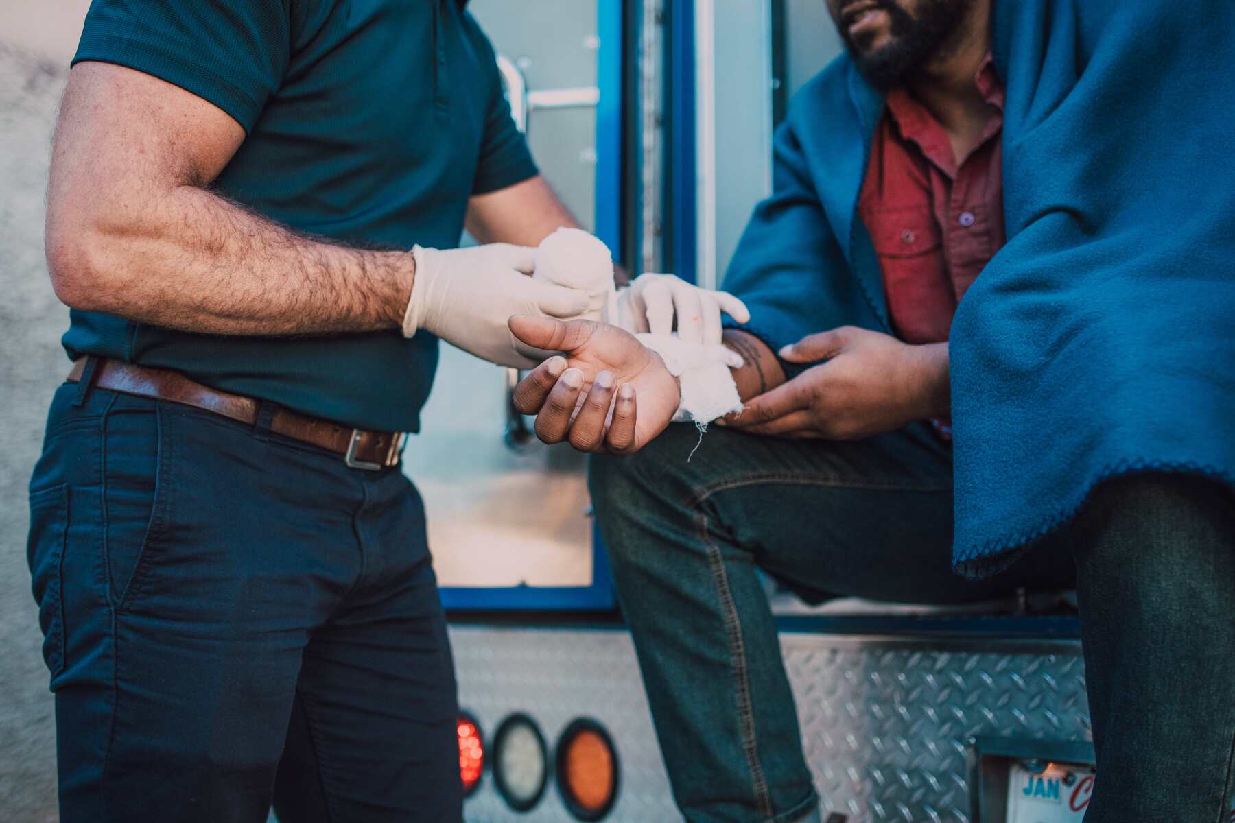 A rescue person putting bandages on a man who got on an accident