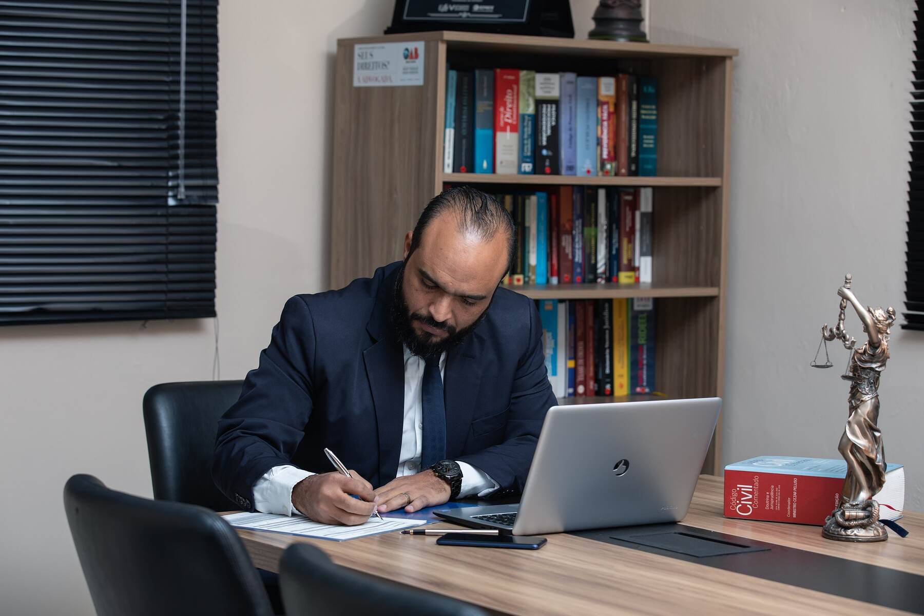 Lawyer signing documents while his laptop is on the table