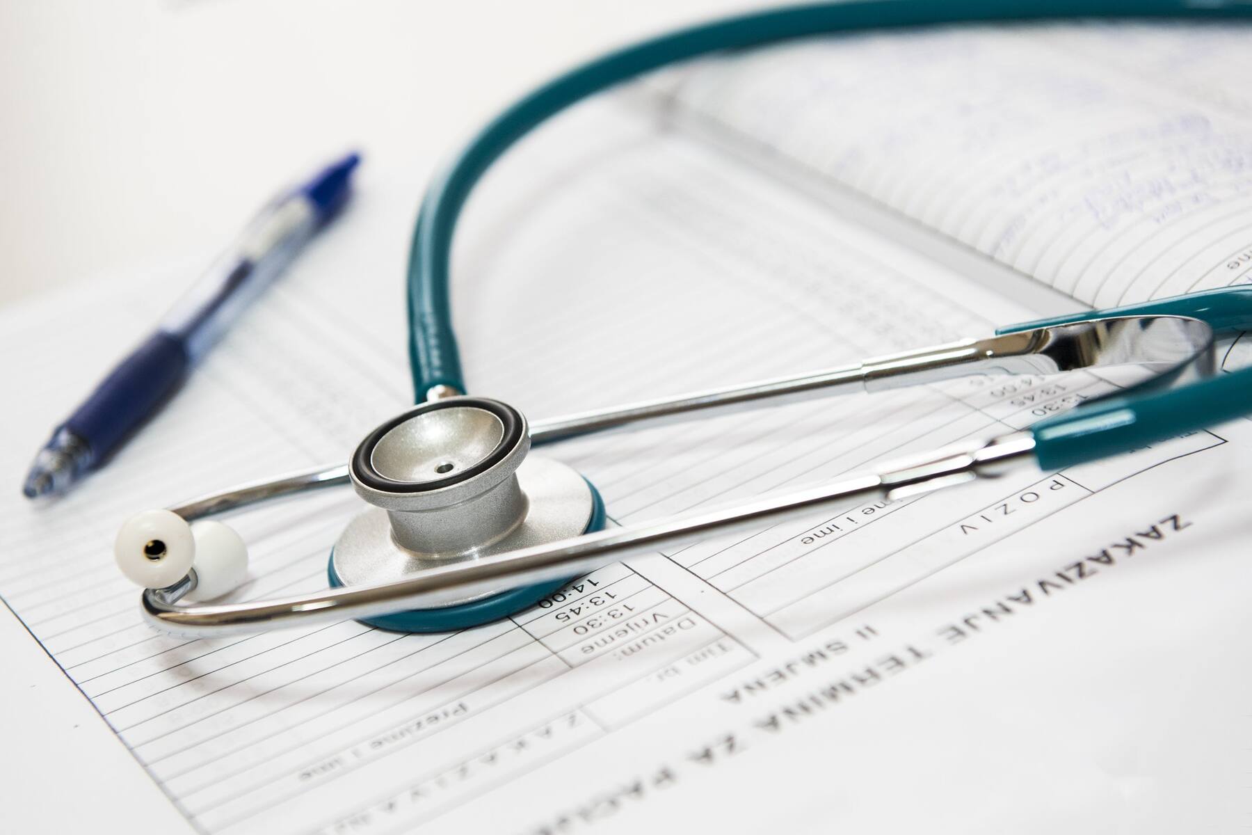 A stethoscope and a pen on top of a medical report