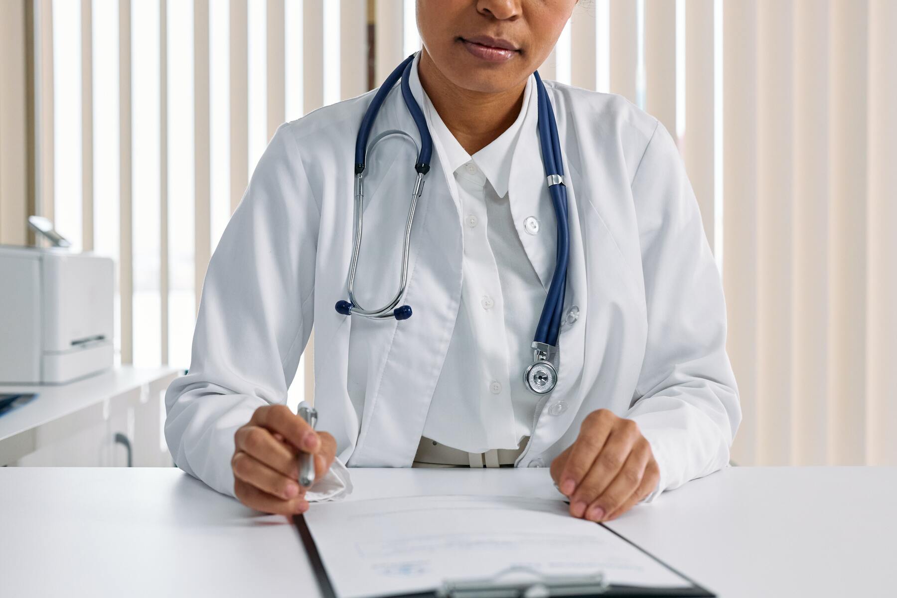 A female doctor looking at a medical report while holding a pen