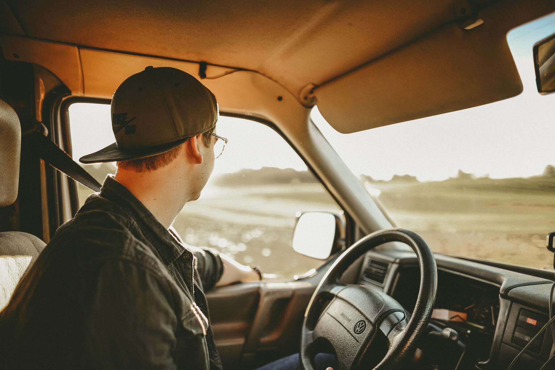 Man looking at his side window while driving a car