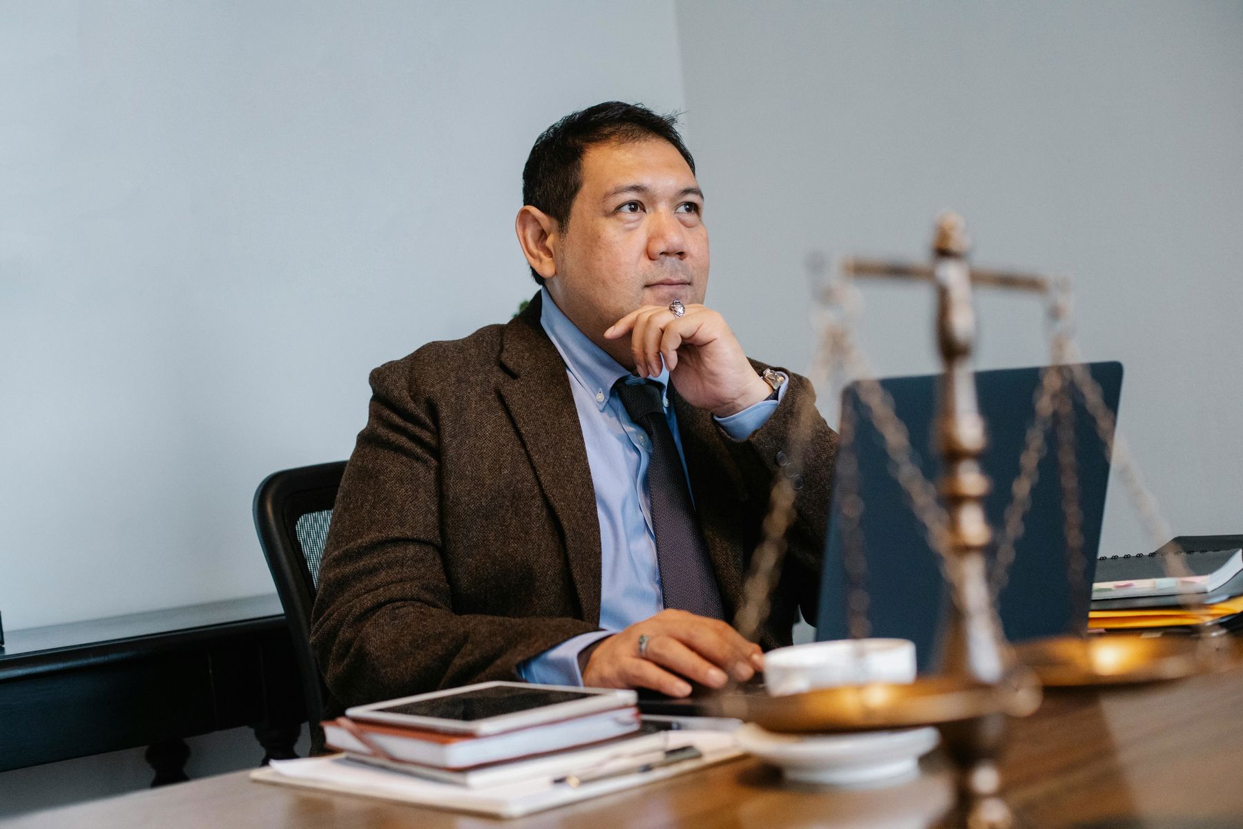 Man with his hand on his chin with a far away look while he's seated on his office