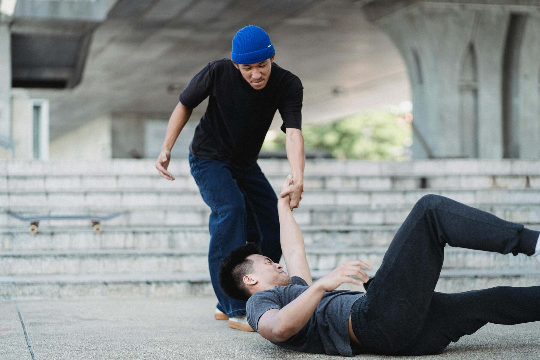 Man helping someone who fell on his back on the pavement