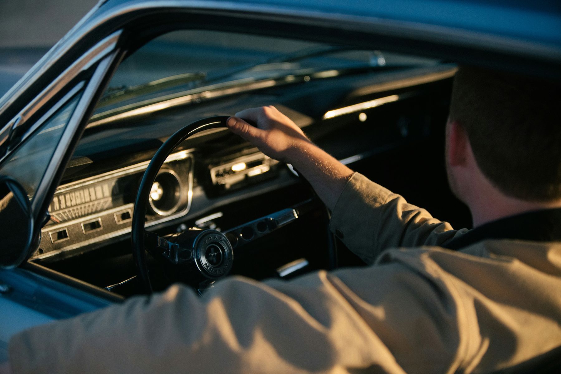 Man with one hand on a steering wheel while driving