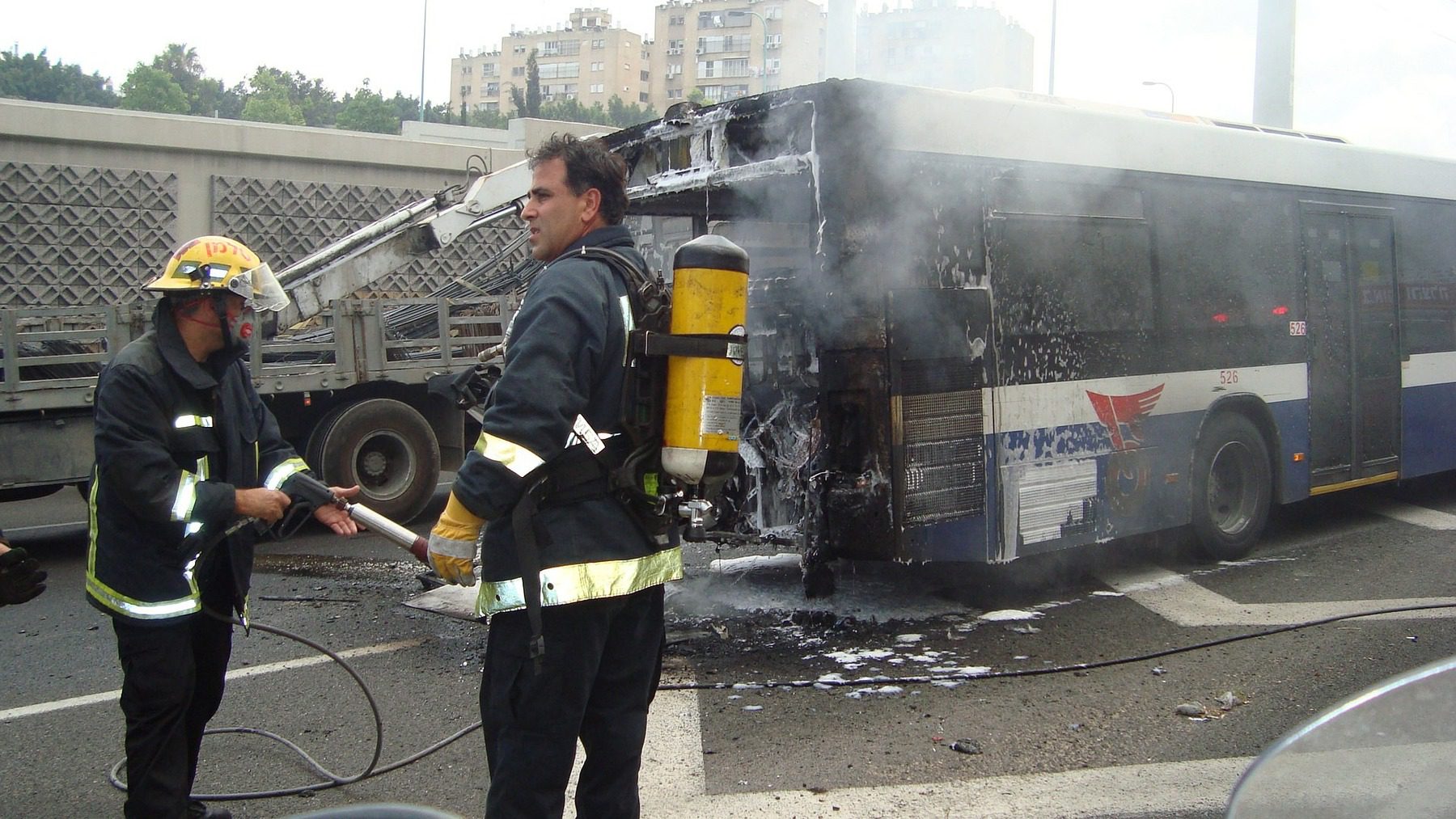Firefighters hosing down a burning bus