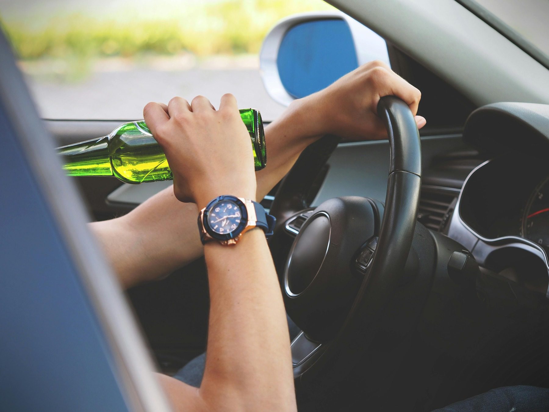 Man drinking a bottle of beer while driving a car