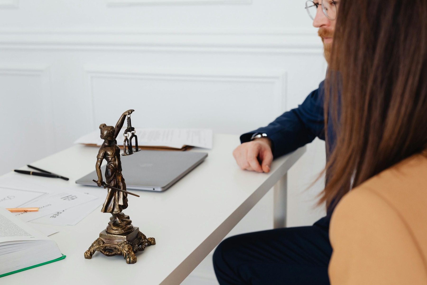 Lady justice statue on a table where two people are talking about a case