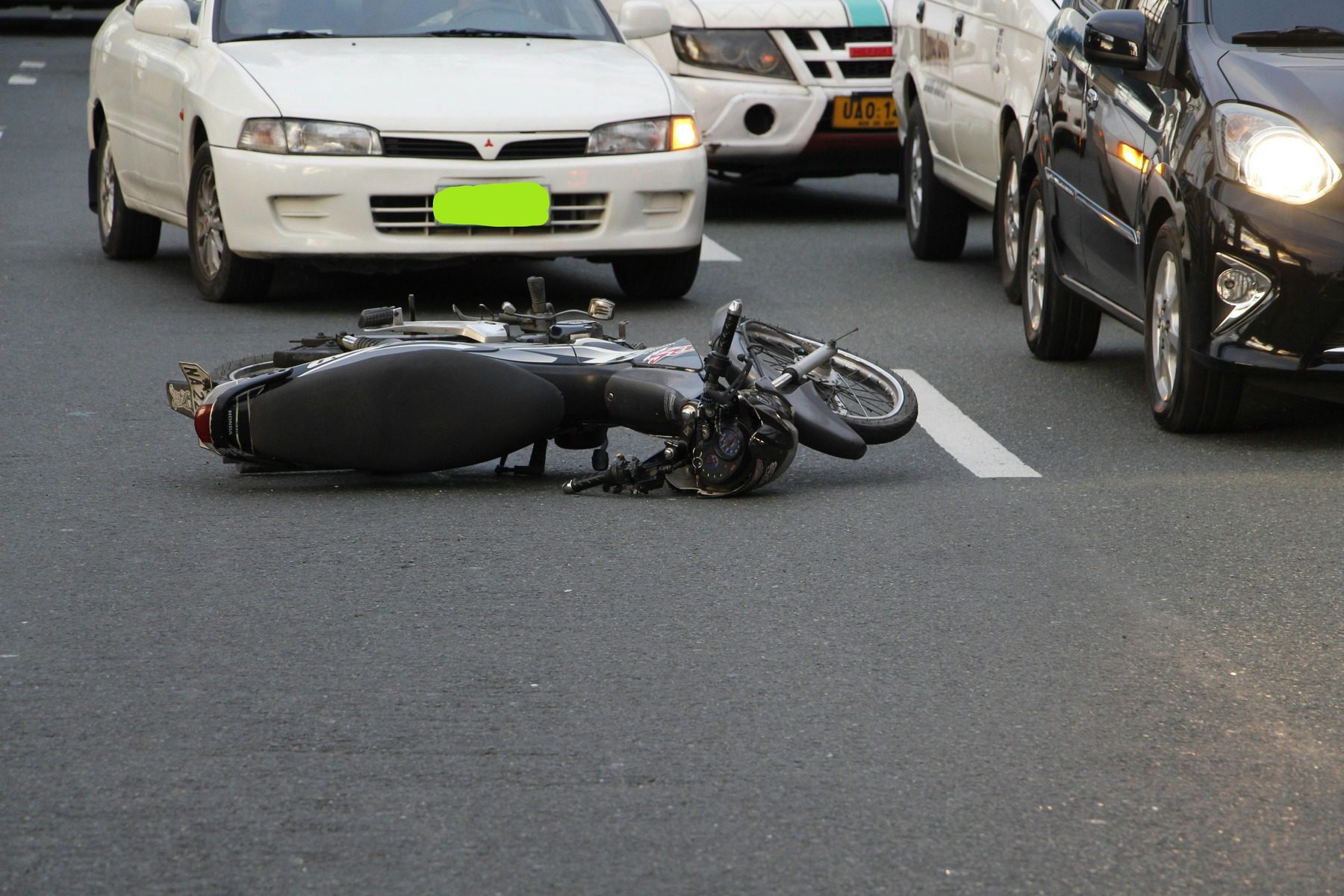 Motorcycle left lying on the road while cars are passing by
