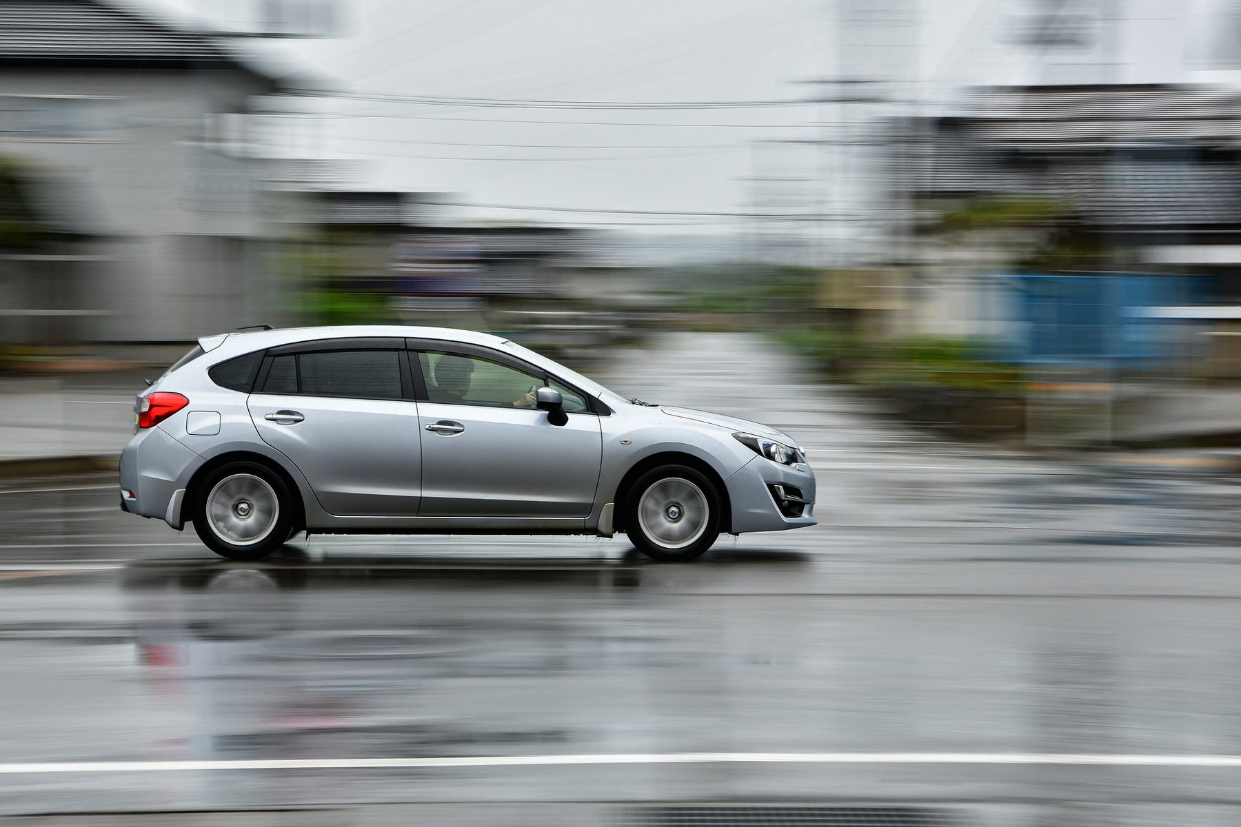 Silver car speeding very fast on an empty road