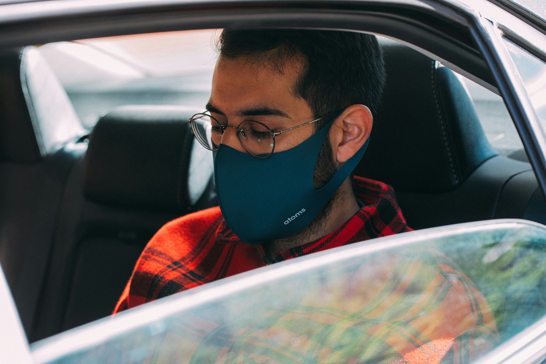 Man wearing a blue face mask while sitting on a rideshare vehicle