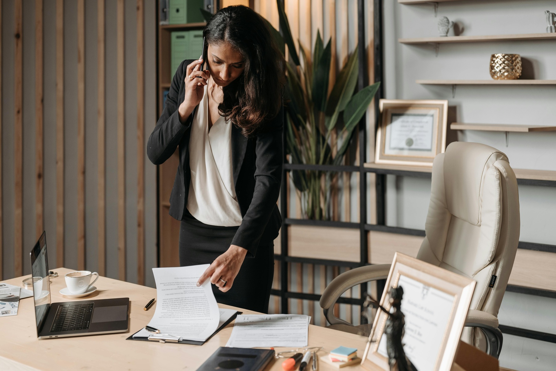 Female lawyer talking on the phone while checking her clipboard on the table