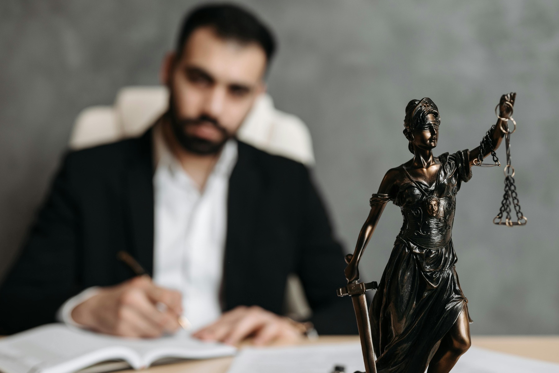 An attorney on the background with the woman of justice figurine in front