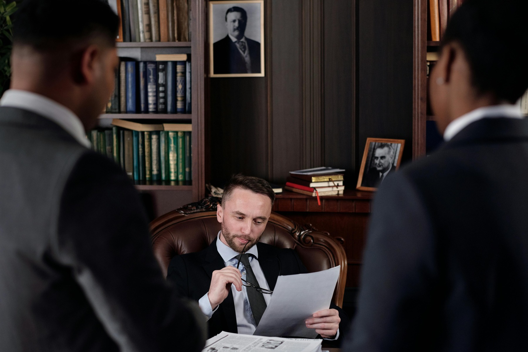An attorney sitting on his table with the two other attorney looking at him