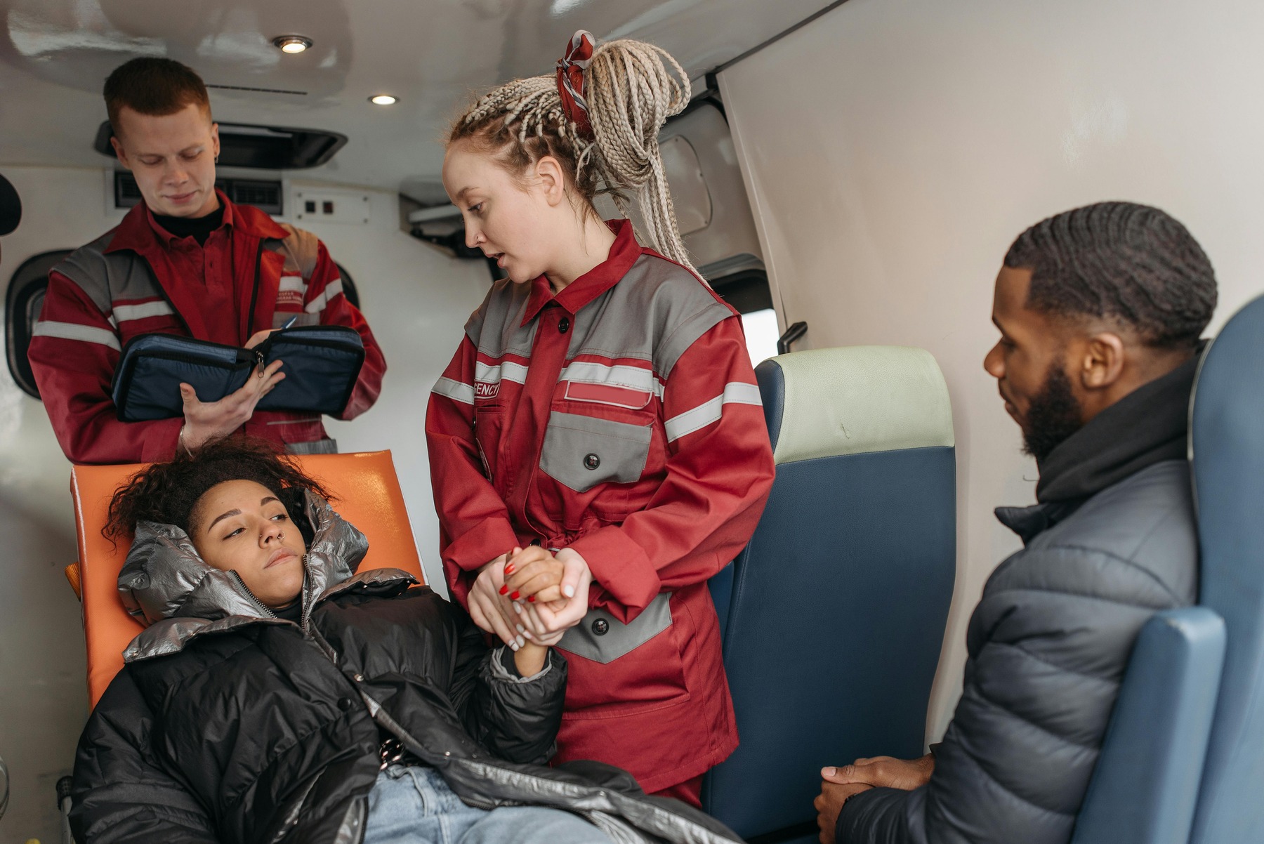 Paramedics checking on a female patient on a stretcher for injuries