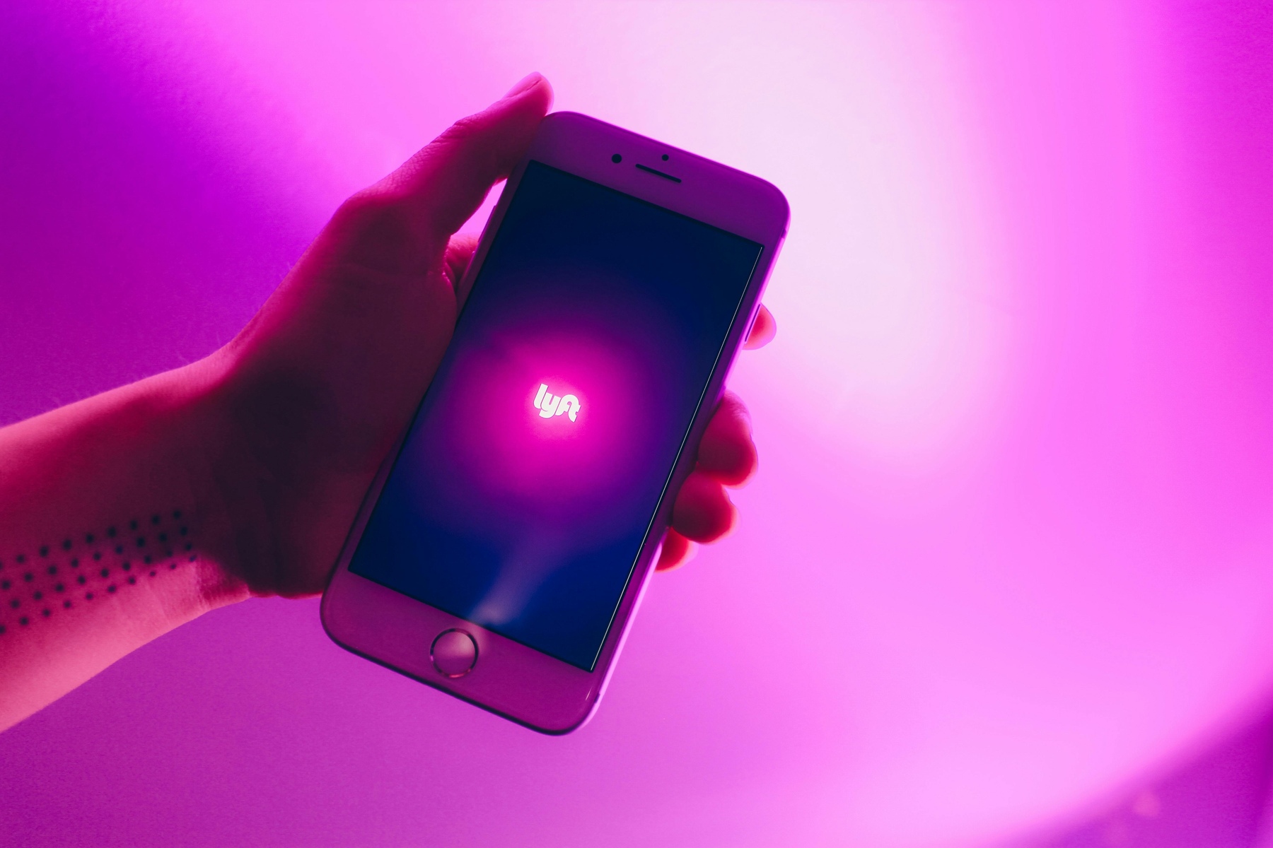 Person holding a mobile phone with the Lyft app visible on the screen