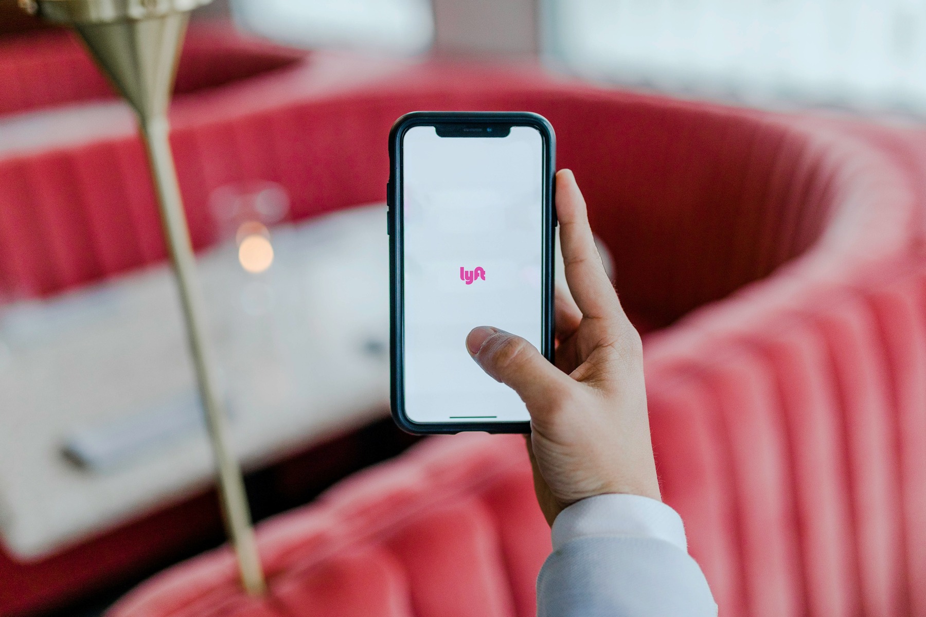 Person holding a mobile phone with a Lyft app on its screen
