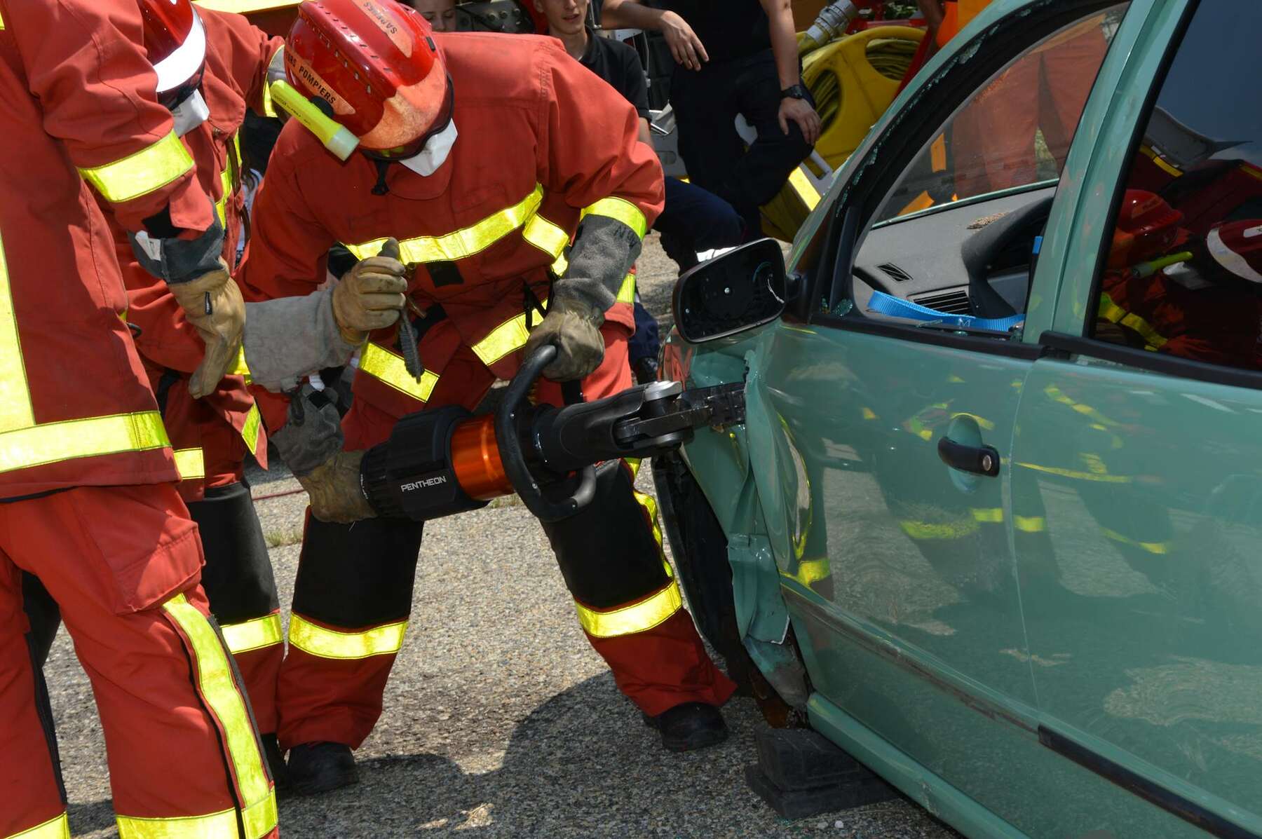 Firefighters use hydraulic rescue tools to open a damaged car door